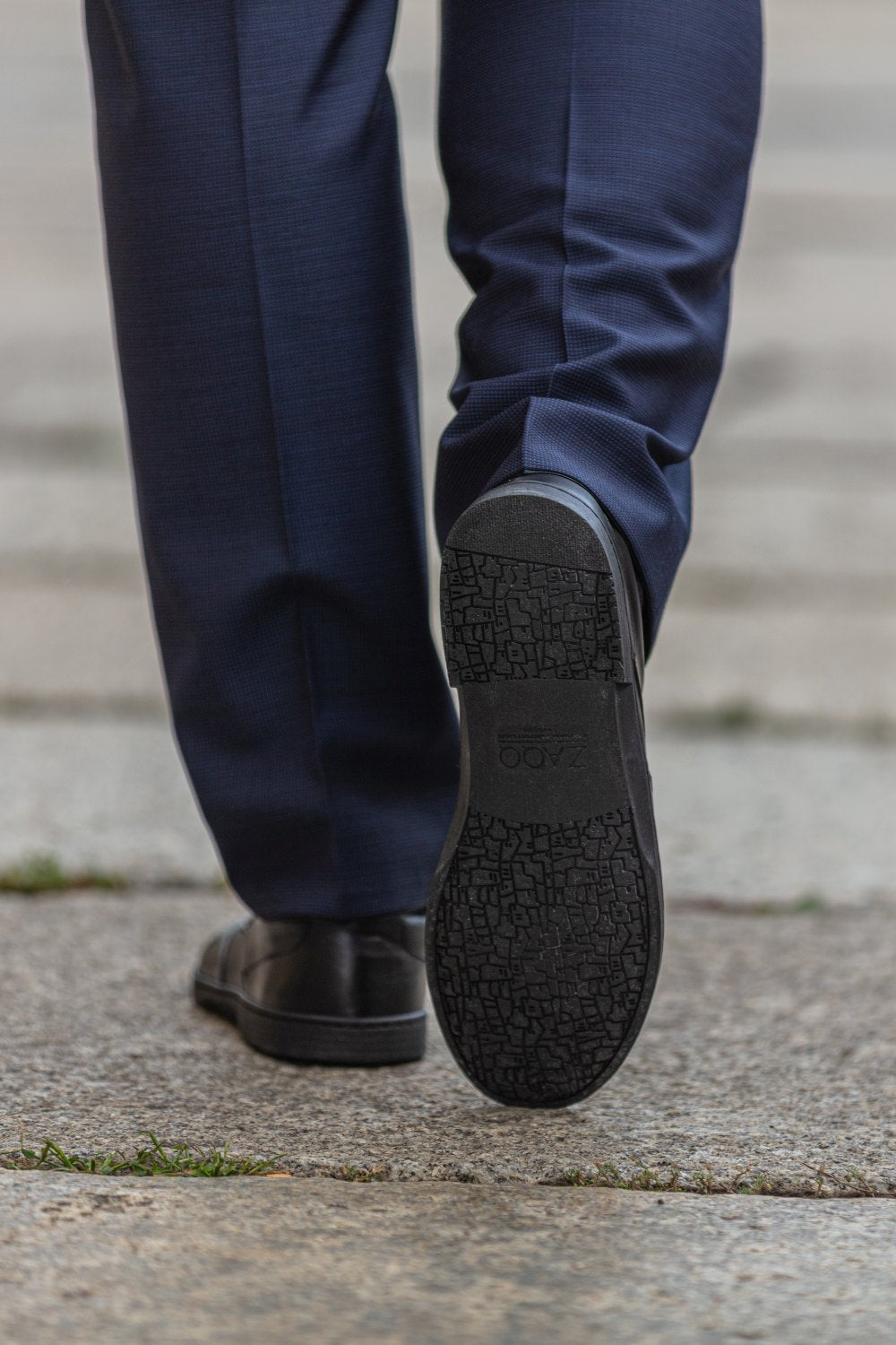 Ein Paar Oxford-Schuhe aus schwarzem Leder BRIQ Prime von ZAQQ mit Schnürung, bei der ein Schuh auf dem anderen vor einem weißen Hintergrund ruht. Diese eleganten Business-Schuhe strahlen Raffinesse aus und sind mit einer bequemen Barfußsohle für ganztägiges Tragen ausgestattet.