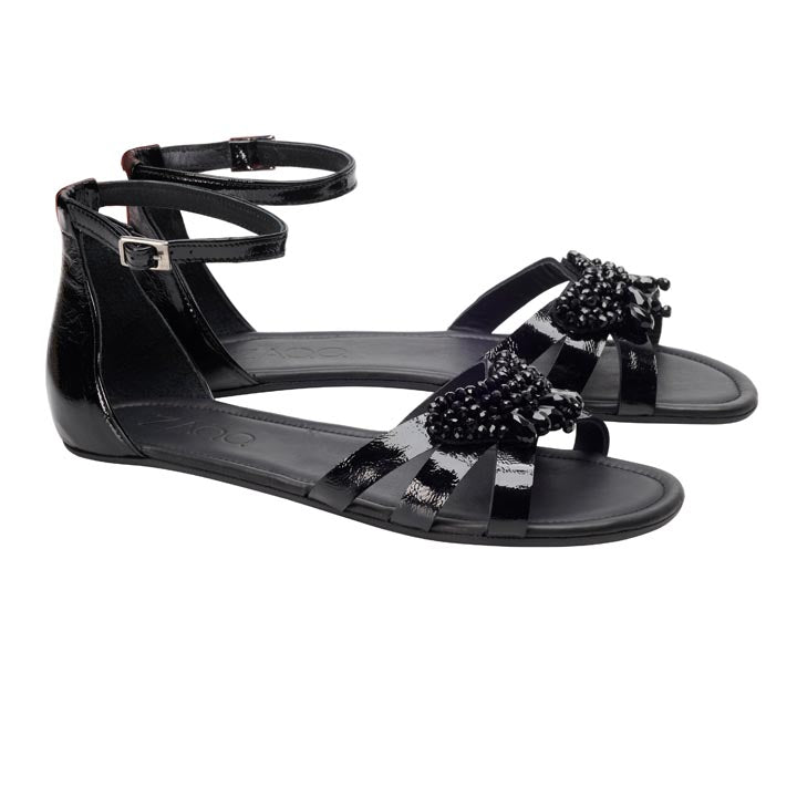 Die schwarzen Sandalen ZAQQ QISELLE haben glänzende schwarze Knöchelriemen mit Schnallenverschluss und sind vorne mit dekorativen Perlenverzierungen verziert. Diese eleganten flachen Sandalen bieten eine perfekte Mischung aus Stil und Komfort für jeden Anlass.