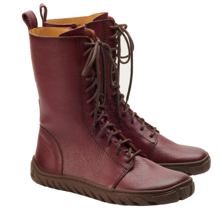 Eine Seitenansicht eines Paars DOQS Bordeaux High-Top-Lederschnürstiefel von ZAQQ zeigt ihre dunkelrote Farbe und die braunen Sohlen. Diese Stiefel aus hochwertigem Nappaleder verfügen über eine strukturierte Oberfläche und ein schlankes, modernes Design, während die ULTRAGRIP-Sohle für zusätzlichen Halt sorgt.