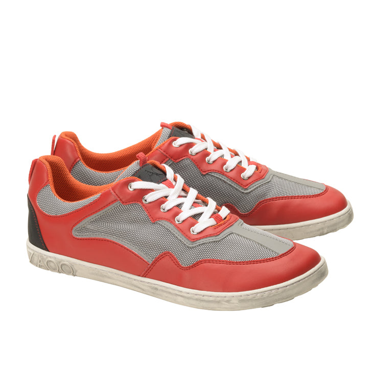 Ein Paar ZAQQ QOPA Red-Sneaker in Rot und Grau mit weißen Schnürsenkeln und orangefarbenen Akzenten. Diese atmungsaktiven Schuhe haben eine strukturierte Sohle und ein Mesh-Gewebe, um eine optimale Luftzirkulation zu gewährleisten. Sie werden elegant nebeneinander vor einem makellos weißen Hintergrund präsentiert.