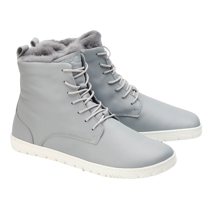 Die QUINTIC Winter Blue Grey High-Top-Stiefel von ZAQQ sind aus Nappaleder gefertigt und haben weiße Sohlen und ein warmes Fellfutter. Mit Schnürung vorne und einem schlanken Design sind diese stilvollen Stiefel ideal für kaltes Wetter. Nebeneinander angeordnet vor einem weißen Hintergrund bieten sie eine perfekte Mischung aus Eleganz und Funktionalität.