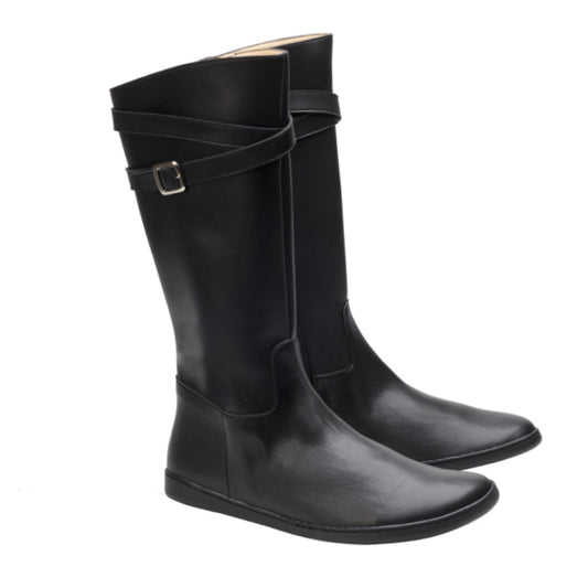 Wir präsentieren den ATTRAQT Vegan Black von ZAQQ: Diese eleganten kniehohen Stiefel zeichnen sich durch ein schlichtes, minimalistisches Design aus. Sie verfügen über einen umlaufenden Riemen mit einer kleinen Schnalle oben, eine abgerundete Spitze und flache Sohlen für ultimativen Komfort. Vor einem schlichten weißen Hintergrund strahlen sie Raffinesse und zeitlosen Stil aus.