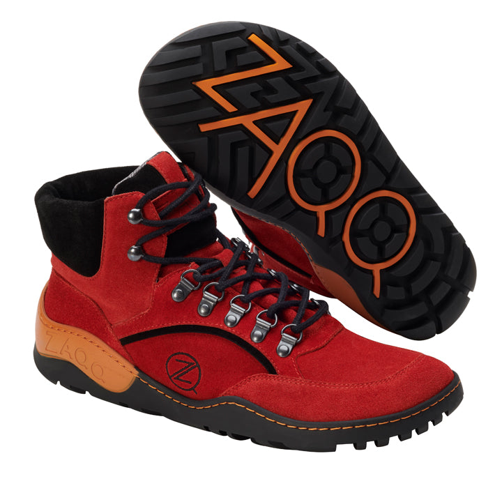 Die TREQ Orange Waterproof Wanderstiefel von ZAQQ haben ein Obermaterial aus Veloursleder in Rot, ergänzt durch schwarze und orangefarbene Sohlen. Sie haben schwarze Schnürsenkel, die durch Metallösen verlaufen und ein seitliches Logo einrahmen. Diese Stiefel zeichnen sich durch ein ausgeprägtes Profilmuster und gemischte Texturen aus, zusammen mit der ZAQQ TERRA Sohle für ultimativen Komfort.