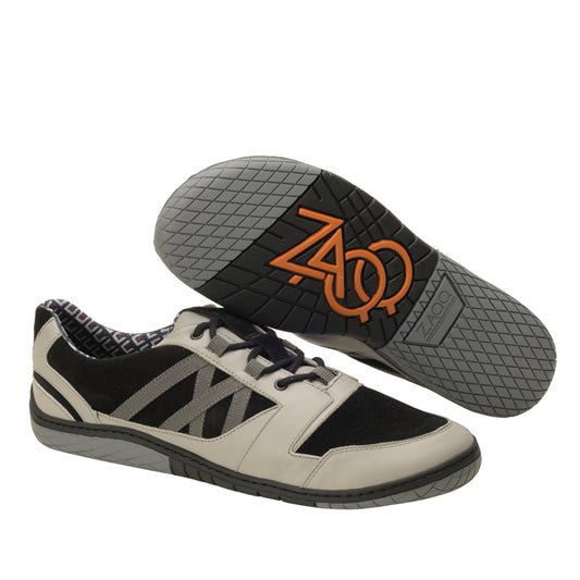 Wir präsentieren die QENDRIQ Black Grey Sneaker von ZAQQ. Diese lässigen Sportschuhe zeichnen sich durch ein unverwechselbares Design in Schwarz- und Grautönen aus. Ein Schuh wird oben mit Schnürsenkeln präsentiert, während der andere mit der Sohle versehen ist und ein kompliziertes Muster auf der ZAQQ MINIMAL Sohle sowie ein orangefarbenes ZAO-Logo aufweist. Die Innenseite der Sneaker weist ein schickes Karomuster auf.