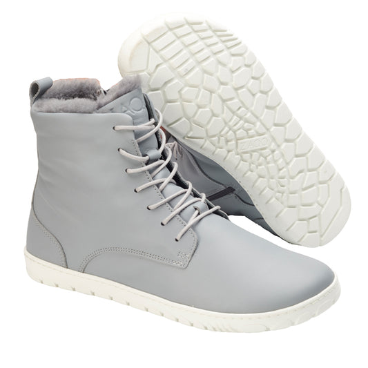 Wir präsentieren die QUINTIC Winter Blue Grey Sneaker von ZAQQ: ein Paar High-Top-Sneaker aus luxuriösem Nappaleder in einem hellgrauen Farbton mit weißen Sohlen. Diese stylischen Winterstiefel haben einen Schnürverschluss und ein kuscheliges Fellfutter. Ein Schuh steht aufrecht, während der andere geneigt ist und seine mit einem sechseckigen Muster verzierte Sohle zur Schau stellt, was sie zur idealen Wahl für stilbewusste Winterträger macht.