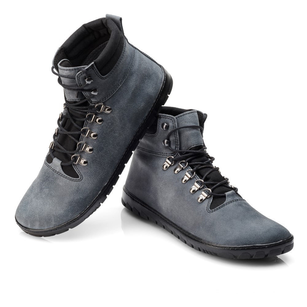 Die EXPEQ Lunar Waterproof Wanderstiefel von ZAQQ sind in einem schicken Dunkelgrau gehalten, ergänzt durch schwarze Sohlen und Schnürsenkel. Sie verfügen über Metallösen und einen gepolsterten Knöchelkragen, perfekt für jedes Outdoor-Abenteuer. Diese Stiefel verfügen außerdem über eine abriebfeste Kautschuksohle und werden kreativ leicht geneigt vor einem schlichten weißen Hintergrund präsentiert.