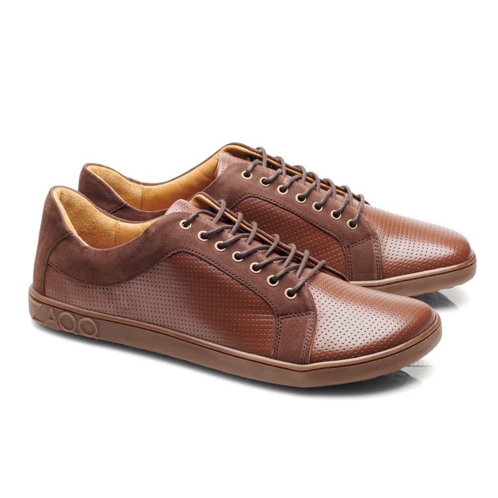 Ein Paar braune Leder-Sneaker im QORE Low Rafter-Stil von ZAQQ mit perforiertem Design und braunen Schnürsenkeln. Diese atmungsaktiven Sneaker haben ein niedriges Profil mit einer Gummisohle und vereinen Komfort und Stil perfekt.