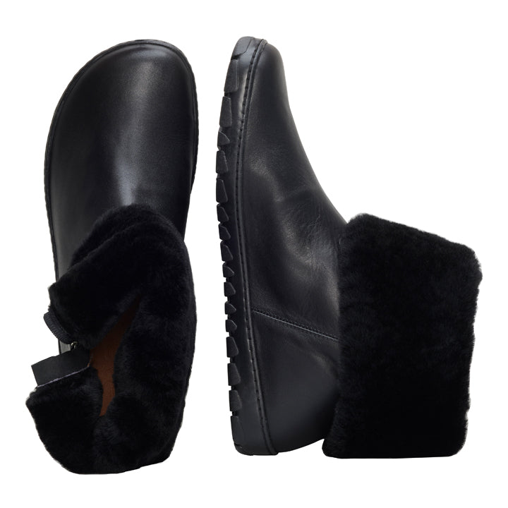 Wir präsentieren den HUQ Winter Black von ZAQQ: Ein Paar schwarze Winterstiefel, fachmännisch gefertigt aus hochwertigem Nappaleder mit einer robusten Kautschuksohle. Ein Stiefel zeigt eine elegante Seitenansicht mit einem umgeschlagenen Schaft, der das weiche, schwarze Fellfutter enthüllt, während der andere Stiefel aufrecht steht und seine strukturierte Sohle hervorhebt.