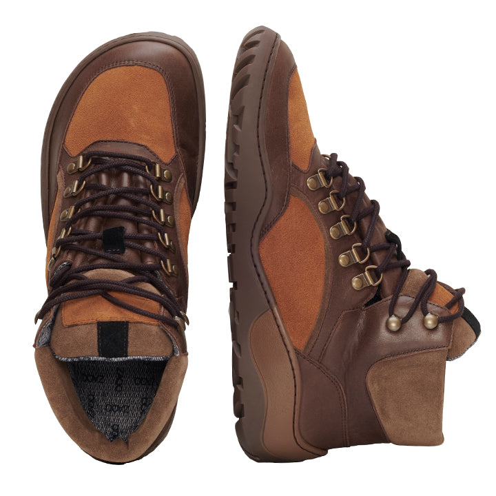 Die wasserdichten TERRAQ Camel-Stiefel von ZAQQ sind aus einer Kombination aus dunkelbraunem Leder und Wildleder gefertigt, ergänzt durch Metallösen und dicke Schnürsenkel. Diese Wanderstiefel sind für Outdoor-Abenteuer konzipiert und verfügen über robuste Sohlen für zuverlässigen Halt. Auf dem Bild steht ein Stiefel aufrecht, während der andere auf der Seite liegt, um das Innendesign zu präsentieren.