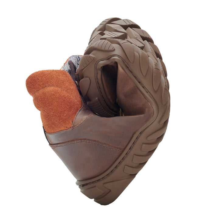 Der WALQ Brown Waterproof Schuh von ZAQQ aus braunem Veloursleder und flexibler, robuster Sohle ist in der Mitte gebogen, um seine Flexibilität und Haltbarkeit zu demonstrieren. Ergänzt wird dieser Barfußschuh durch ein kontrastierendes orangefarbenes Stofffutter.