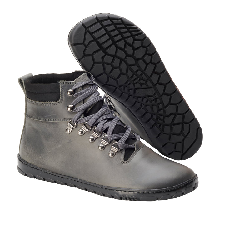 Ein Paar wasserdichte EXPEQ Wide Grey High-Top-Wanderstiefel von ZAQQ hat schwarze Schnürsenkel und Metallösen. Ein Stiefel steht aufrecht, während der andere geneigt ist und seine schwarze, strukturierte Sohle mit geometrischem Muster zeigt. Diese robusten wasserdichten Stiefel sind perfekt für Outdoor-Abenteuer und auf Haltbarkeit und Komfort in anspruchsvollem Gelände ausgelegt.