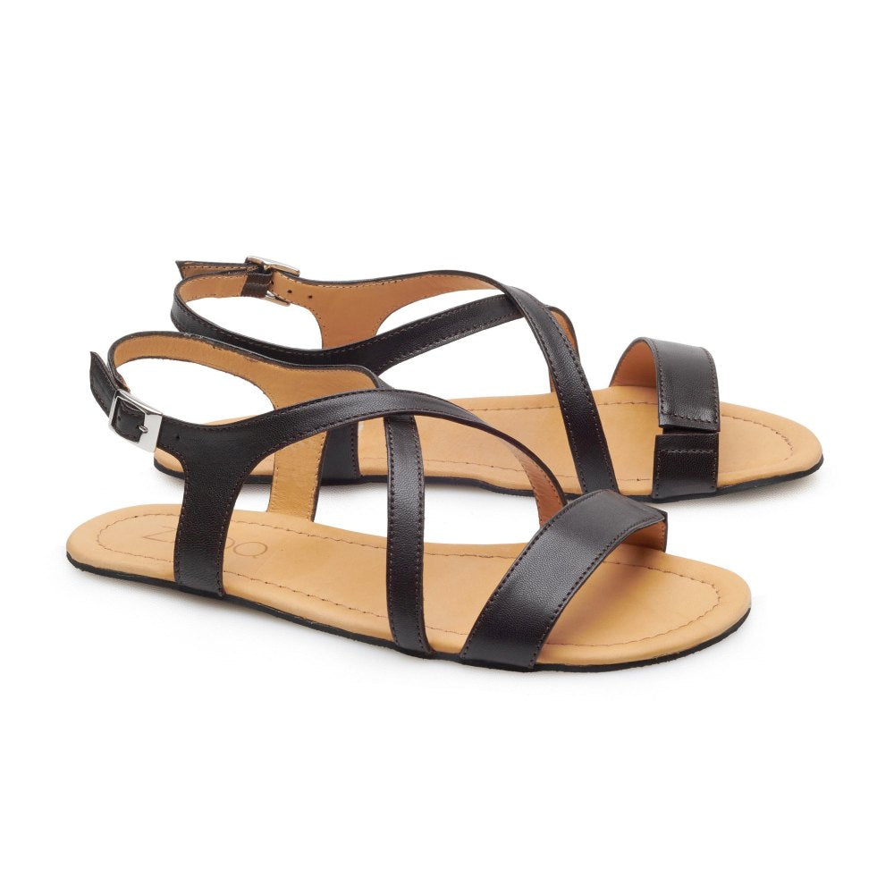 Die ZAQQ QEE Dark Brown Sandalen sind minimalistisch im Design und bestehen aus dunkelbraunem Riemchenleder mit flachen Gummisohlen und einem Schnallenverschluss. Diese eleganten Schuhe haben eine offene Spitze und einen Knöchelriemen, der sich vor einem schlichten weißen Hintergrund abhebt.