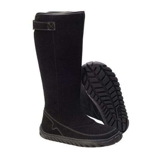 Ein Paar raffinierte, schwarze wasserdichte QRAFT-Kniestiefel von ZAQQ, aus schwarzem Wildleder gefertigt und mit einem Klettverschluss an der Oberseite sowie einer ULTRAGRIP-Sohle für außergewöhnlichen Halt ausgestattet. Ein Stiefel steht aufrecht, während der andere anmutig dagegen lehnt und das aufwendige Profildesign hervorhebt.