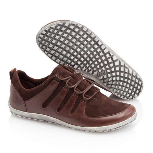 Die ZAQQ SHOQQ Dark Brown Sneaker kombinieren Leder und Wildleder für einen schicken Look, der durch weiße Gummisohlen abgerundet wird. Diese Barfußschuhe haben dekorative Schnürsenkel und ein einfaches Slip-On-Design, wobei ein Schuh das Gittermuster auf seiner Sohle hervorhebt.