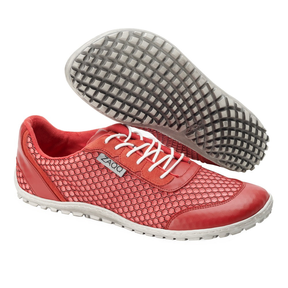 Ein Paar ultramoderne Sportschuhe TOQIO Red von ZAQQ mit strukturiertem Mesh-Design, weißen Sohlen und Schnürsenkeln. Ein Schuh ist von der Seite abgebildet und trägt den Markennamen ZAQQ, während der andere die gemusterte Sohle zeigt.