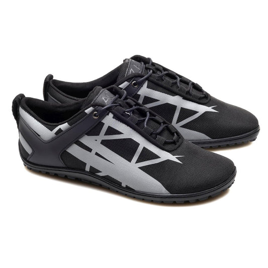 Die XIQOT Black Sportschuhe von ZAQQ präsentieren ein elegantes schwarzes Design mit grauen geometrischen Mustern an den Seiten, ergänzt durch schwarze Schnürsenkel und einen Low-Cut-Stil. Diese Schuhe bestehen aus veganem Meshgewebe und verfügen über eine flexible Kautschuksohle. Mit ihrer strukturierten Sohle bieten sie Haltbarkeit und Halt und eignen sich perfekt für Freizeitausflüge oder sportliche Aktivitäten.