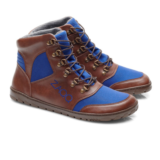 Die HIQE Brown Blue Waterproof High-Top Sneaker von ZAQQ bestehen aus braunem Leder mit blauen Stoffakzenten und Haken- und Ösenschnürung. Der Markenname ist seitlich in Blau aufgestickt. Diese stylischen Outdoorboots haben eine synthetische Sohle, ein graues gepolstertes Innenfutter und eine wasserdichte Membran.