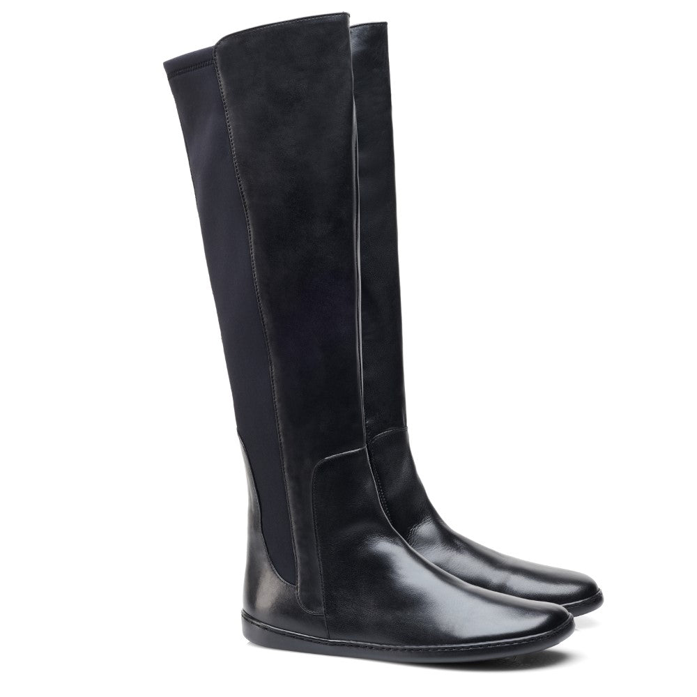 Wir präsentieren die QATCH Winter Black-Stiefel von ZAQQ, ein stilvolles Paar hoher schwarzer Lederstiefel mit elegantem Design, glatter Oberfläche und Kautschuksohle. Diese Stiefel zeichnen sich durch eine stromlinienförmige Silhouette aus und reichen bis knapp unters Knie.