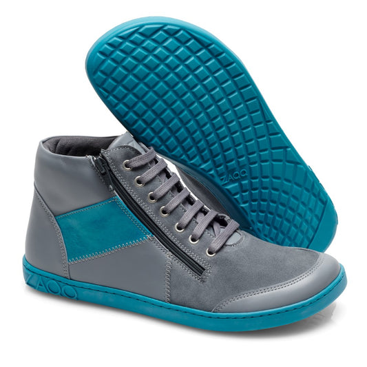 Wir präsentieren den LUQQ Turquoise von ZAQQ: Ein Paar stylische Midcut-Sneaker mit grauem Obermaterial und blaugrünen Akzenten. Diese Schuhe verfügen über praktische seitliche Reißverschlüsse, Schnürsenkel und eine leuchtend türkisfarbene Kautschuksohle mit einem strukturierten Muster für besseren Halt.