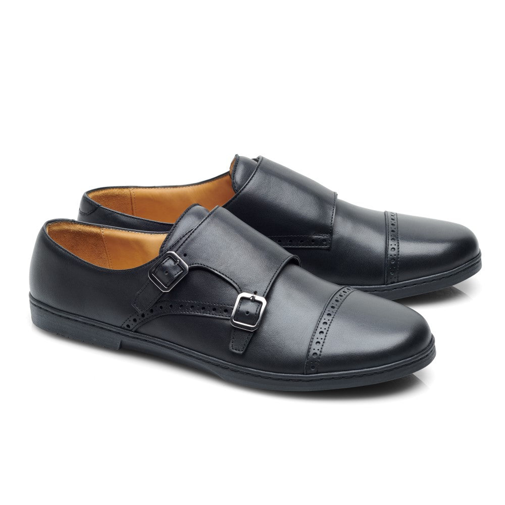 Die MONQ Captoe Black von ZAQQ sind ein Paar schwarze Monkstrap-Schuhe aus Leder mit Doppelschnallendesign und Brogue-Details an der Zehenkappe, die Eleganz ausstrahlen. Diese Businessschuhe zeichnen sich durch ein glattes, poliertes Finish und ein hellbraunes Innenfutter auf weißem Hintergrund aus.