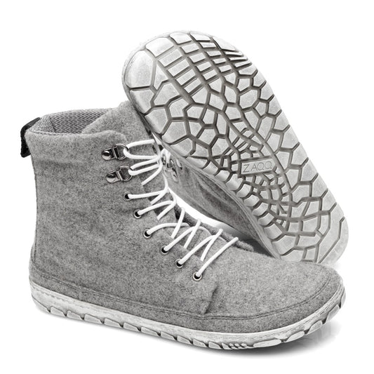 Ausgestellt wird ein Paar QICE Grey High-Top-Sneakers von ZAQQ mit weißen Schnürsenkeln. Ein Schuh steht aufrecht, während der andere angewinkelt ist, um die strukturierte, gemusterte Outdoorsohle hervorzuheben.