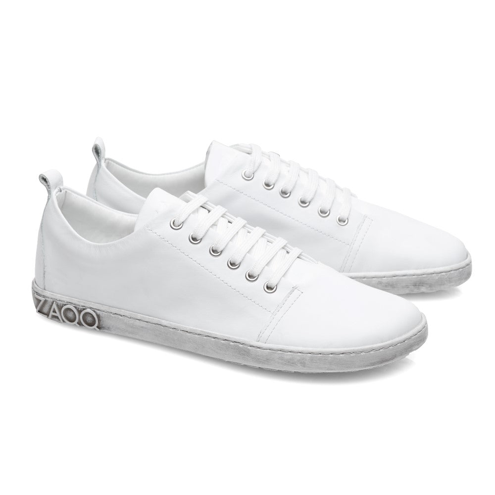 Die ZAQQ TAQQ Nappa White Sneaker bestechen durch hochwertiges Nappaleder mit flexiblen Gummisohlen und weißen Schnürsenkeln. Jeder Schuh trägt auf der Außenseite der Sohle elegant das graue „ZAQQ“-Zeichen und verströmt minimalistischen Charme, wenn man sie nebeneinander auf einem makellos weißen Hintergrund platziert.